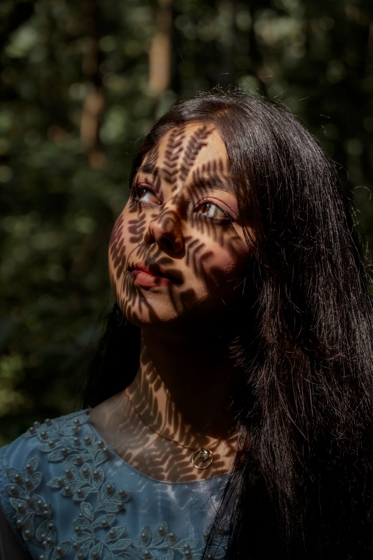 Vrouw met complexe schaduwen van bladeren op haar gezicht in het Dhaka-bos. Boeiende lichtspel.