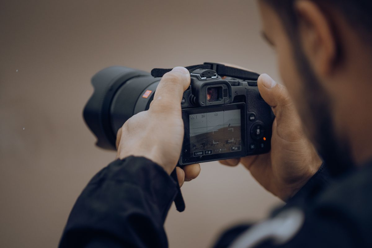 Detailopname van een fotograaf die buitensettings op een digitale camera aanpast.